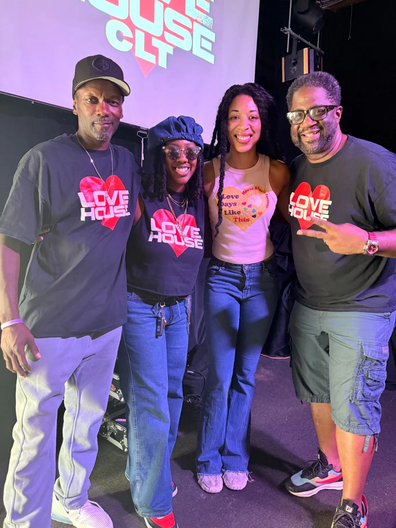 LoveHouse crew members in branded tees pose in front of a LoveHouse CLT screen.